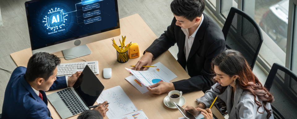A group of business professionals sit at a table discussing how to implement artificial intelligence into their work.