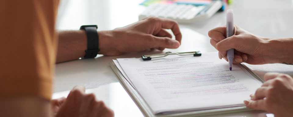 a close up of two individuals' hands as they complete paperwork ensuring they are providing ethical treatment and services